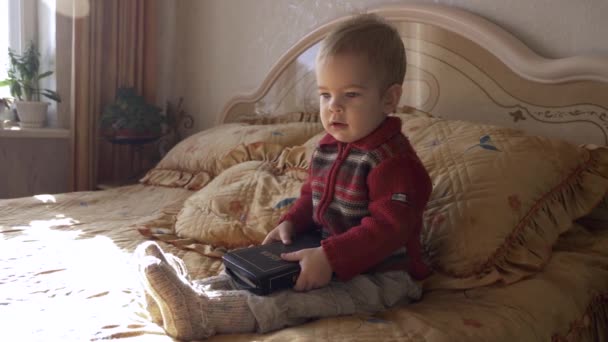 小さな子供聖書の寝室でベッドに座っています 開く本とターンのページ — ストック動画