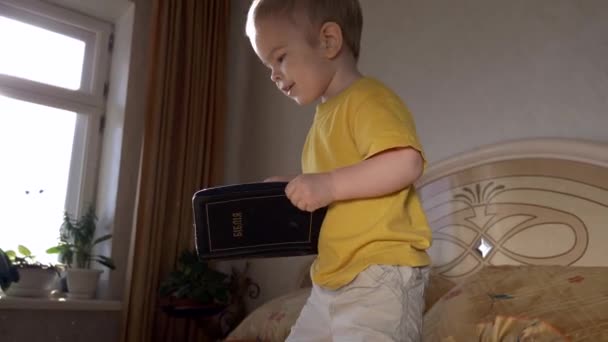 Pequena Criança Senta Com Bíblia Cama Quarto Abre Livro Vira — Vídeo de Stock