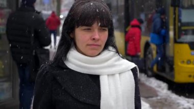 Üzgün esmer kadın kar yağışı sırasında şehir sokak üzerinde yürür. Yavaş hareket su saç bırakır. Kış
