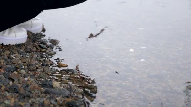 美丽的黑发人坐在河岸上思考和寻找水 慢动作冬季 — 图库视频影像