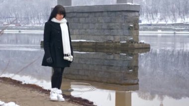 Üzgün bir duygu ile güzel kadın nehir banka düşünme üzerinde yürür. Kış yavaş hareket