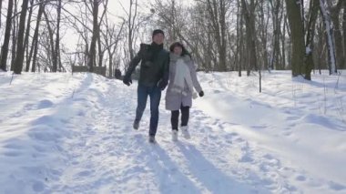 Mutlu çift el ele tutuşarak Winter Park karda çalıştırın. Ağır çekim kar güneşli gün 