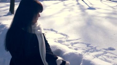 Kelime aşk ve kar üzerinde çizilmiş kalpleri yakın yalnız kız oturuyor. Winter Park güneşli bir günde. Ağır çekim 30 fps 1/2 gerçek zamanlı hız 60 fps