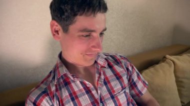 Laptop sörf Internet kullanan genç adam kanepe kanepeye oturur. Ağır çekim 30p 0,5 gerçek zamanlı hız 60p