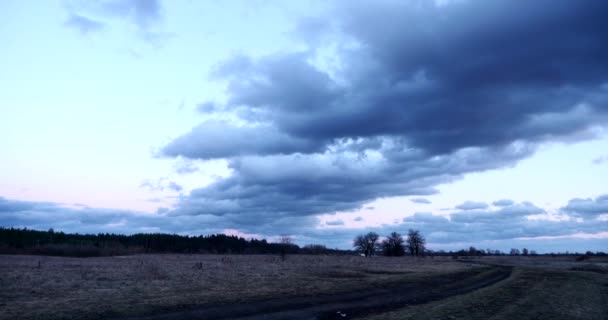 夜の雲の景色グローブの農村道路の近くの川の上の夕日 田舎の風景日木を通して輝きます 劇的な雲が吹く風 季節変更秋冬の春時間 夕方オレンジ Blue Sky — ストック動画