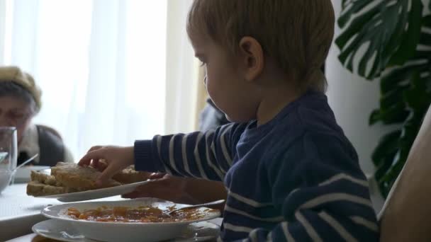 小さな子供はパンを取り スープに追加します 食事を楽しむディナーを持つ多世代の家族 スローモーション0 5速度60 Fps — ストック動画