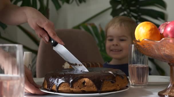 Mão Feminina Corta Torta Chocolate Com Faca Cozinha Criança Observando — Vídeo de Stock