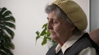 Yaşlı, üzgün, yaşlı bir kadının portresi. Yaşlı, büyük büyükannenin hayatı hakkında düşünmesi. Koltukta sakin oturması hakkında. Yavaş çekim 0. 5 hız