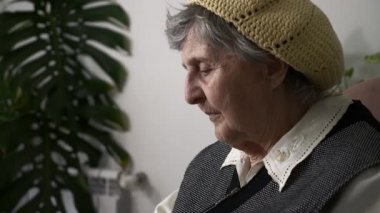 Yaşlı, üzgün, yaşlı bir kadının portresi. Yaşlı, büyük büyükannenin hayatı hakkında düşünmesi. Koltukta sakin oturması hakkında. Yavaş çekim 0. 5 hız