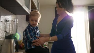  Genç Anne Oğlu Öpüyor. Mutfak tezgahında oturan çocuğu okşayan kadın. Pencereden Sabah Akşamı Güneşi. 2x Yavaş çekim, 0.5 hız 60 FPS