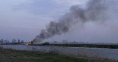 WF6 Wildfire Nehir kenarındaki tarlada yanıyor. Kuru Çimen Ovası 'nda yangın. Sabah Akşam Manzarası. Kış Mevsimi Kırsal Arazi