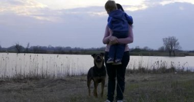 Anne, Küçük Oğul 'a sarıldı. Nehrin yanındaki arazide yürüyüş ve yürüyüş. Kırsalda Sabah Akşamı. Bahar Zamanı Bahar Akşamı