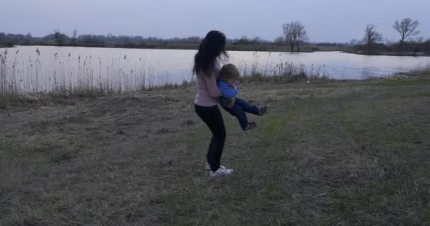 Mãe Girando Redor Com Criança Mãos Jogando Campo Perto Rio — Vídeo de Stock