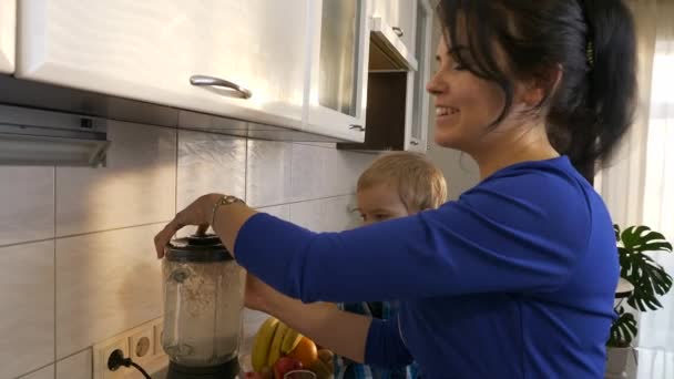 母子俩在搅拌机里用发芽的小麦酿制水果鸡尾酒 小孩坐在厨房台面上 晨光透过窗户照进来 2X慢动作 5速度60 Fps — 图库视频影像