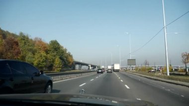 Şehir Otobanı boyunca giden araba. Ön cam Ön ekran Başlıklı Kız Görünümü. Ukrayna Kyiv 2018. Parlak güneşli yaz sonbahar sabahı, mavi gökyüzü. 2x Yavaş çekim 0. 5 hız 60 FPS