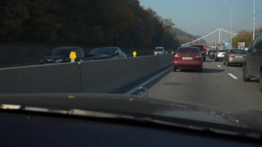 Şehir Otobanı 'nda trafik sıkışıklığında araba hareket ediyor. Ön cam kaput görüntüsü. Arabalar şehir caddesinde hareket ediyor. Ukrayna Kyiv 2018. Parlak güneşli yaz sonbahar sabahı, mavi gökyüzü. 2x Yavaş çekim 0. 5 hız 60 FPS