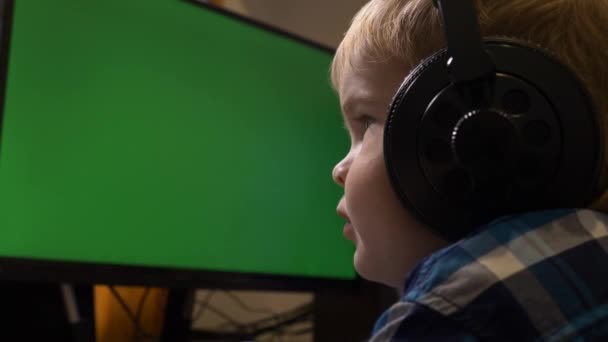 小さな子供が座って緑の画面のモニターの前で見ている フリーランスの父のPcワークステーションの編集 ゲームPc — ストック動画