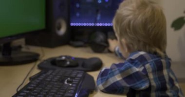 Küçük Çocuk Yeşil Ekran Monitörlerinin Önünde Baş Stüdyo Kulaklığı Takıyor. Müzik dinlemek, video oyunu izlemek. Babamın PC Çalışma İstasyonu. 10 bit HLG