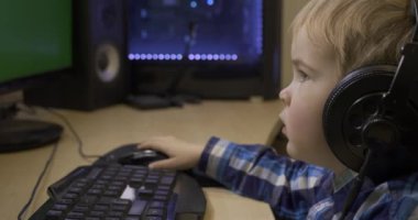 Ciddi Küçük Çocuk Öğreniyor İnternet Videoları İzliyor. Çocuk Yeşil Ekran monitörünün önünde oturuyor. Babamın PC Çalışma İstasyonu. Oyun bilgisayarı. 10 bit HLG