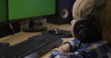 Ciddi Küçük Çocuk Öğreniyor İnternet Videoları İzliyor. Çocuk Yeşil Ekran monitörünün önünde oturuyor. Babamın PC Çalışma İstasyonu. Oyun bilgisayarı. 10 bit HLG
