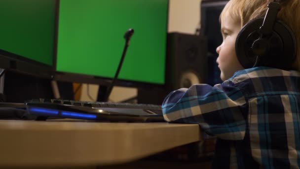 小さな子供サーフィンインターネットコンピュータを使用する学習を見て再生します 少年は緑の画面のモニターの前に座っている 父のPcワークステーションの編集 ゲームPc — ストック動画