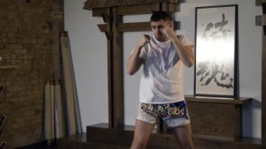 Dövüş Sanatları Dövüşçüsü Elle Yumruk Antrenmanı. Adam Yumruk Yumruk Emiyor. Sporcu Dövüş için Hazırlık Vuruşları yapıyor. Doğu Asya Style Studio 'da Profesyonel Atletizm Eğitimi. 2x Yavaş çekim - 0.5 hız 60 FPS