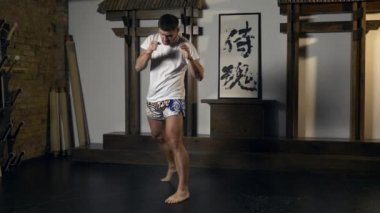 Dövüş Sanatları Dövüşçüsü Tekme ve Yumruk egzersizi yapıyor. Havada Şiddetli Darbeler. Profesyonel Sporcu Yarışmaya Hazırlanıyor. Doğu Asya Style Studio 'da Atletizm Eğitimi. Gölge Dövüşü 2x Yavaş çekim - 0.5 hız 60 FPS