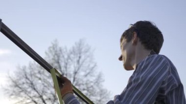 Mezura Ölçüm Cihazıyla Ölçen Genç Adam Arka Bahçe 'de Metal İnşaat Üzerine Kalemle İşaretler Yapıyor. Kırsal kesimde bir ev. Kırsal bölgede bir bahar akşamı. 4K 10-bit Hibrit Günlük Gama HLG HDR