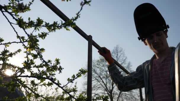 年轻人在后院里焊接金属建筑 护目镜工人 乡郊村舍附近的花园 10位混合对数Gama Hlg Hdr — 图库视频影像
