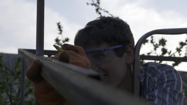 Молодой Человек Измеряет Лентой Рисует Карандашом Метки Металлоконструкции Дворе Сада — стоковое видео