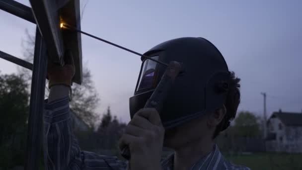 Joven Hombre Soldadura Metal Construcción Patio Trasero Trabajador Casco Protector — Vídeo de stock