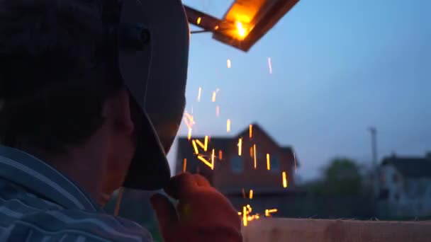 裏庭で若い男溶接金属建設 保護ヘルメットの労働者 田舎のコテージハウスの近くの庭 10ビット — ストック動画