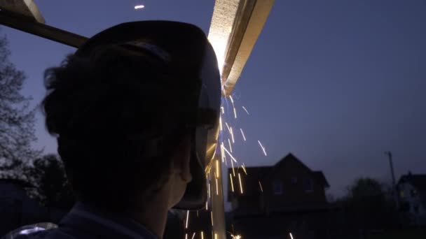 Ung Man Svetsning Metall Konstruktion Trädgården Arbetare Skyddshjälm Trädgårdshus Lantlig — Stockvideo