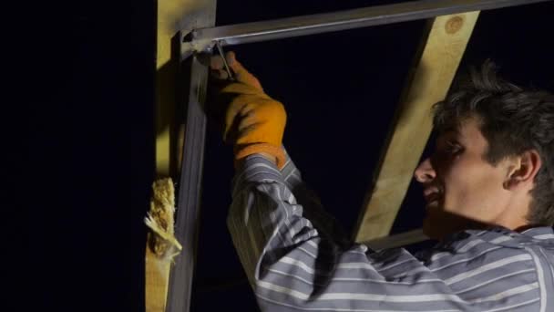 年轻人紧紧抓住木头和金属结构中的螺丝 在夜间建造屋顶 10位 — 图库视频影像