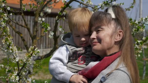 Großmutter Hält Enkel Den Händen Der Natur Blühende Blumen Hinterhofgarten — Stockvideo