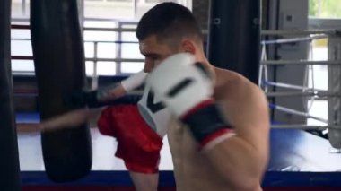 Spor salonunda iki profesyonel boksör yumruklama ve tekme atma torbası boks ringinde. Muay Thai Dövüş Sanatları Dövüşçüleri Antrenmanı. 2x Yavaş çekim 1 / 2 hız 60 fps 4K