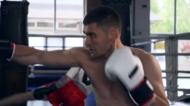 Spor salonunda iki profesyonel boksör yumruklama ve tekme atma torbası boks ringinde. Muay Thai Dövüş Sanatları Dövüşçüleri Antrenmanı. 2x Yavaş çekim 1 / 2 hız 60 fps 4K