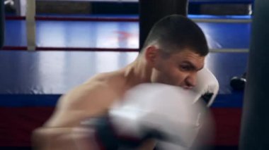 Profesyonel Boksör Spor Salonu 'nda Kum Torbası Vuruyor. Güçlü kaslı adam güçlü itişli yumruklar atıyor. 2x Yavaş çekim 1 / 2 hız 60 fps 4K