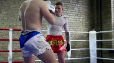 Muay Thai Boksörü Punch Pad 'de Zıplayan Hava Tekmeleri yapıyor. Beyaz Adam Şehir Spor Salonu 'nda Dövüş Sanatları Eğitmeniyle Çalışıyor