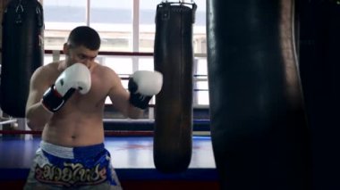 Muay Thai Boksör Tekme ve Yumruk Torbası. Beyaz Adam Şehir Spor Salonu 'nda eğitim görüyor. 2x Yavaş çekim 1 / 2 hız 60 fps 4K