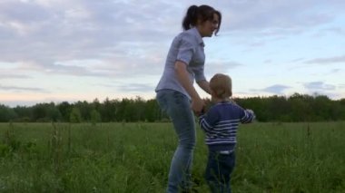 Annesinin etrafında koşan neşeli çocuk. Doğa Sahası 'nda oynuyorum. Akşam Alacakaranlığı Kırsal Sahnesi