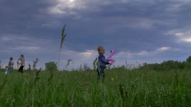 Küçük Çocuk High Grass Field 'da Oyuncak Uçakla Oynuyor. Akşam Alacakaranlığı Kara Bulutlar