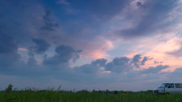 畑の向こうの農村の未舗装道路を移動するヴァン 美しい夕日夕方曇り空の風景 — ストック動画