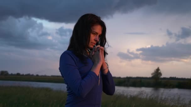 美しい女の子は川とフィールドの近くの農村道路で祈っています 風光明媚な自然の夕暮れ夕暮れ 嵐の雨の天気劇的な雲の空 2倍スローモーション 60Fps — ストック動画