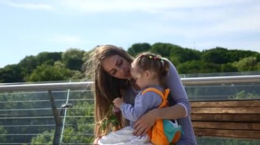 Anne, çocuğuyla birlikte şehir parkındaki Bench 'te oturuyor. Şehir Yeşil Alanı. Parlak Güneşli Yaz Günü