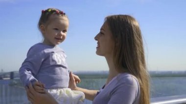 Anne, yaya köprüsünden şehir çevresini gösteren bir kızla konuşuyor. Parlak Yaz Güneşli Günü