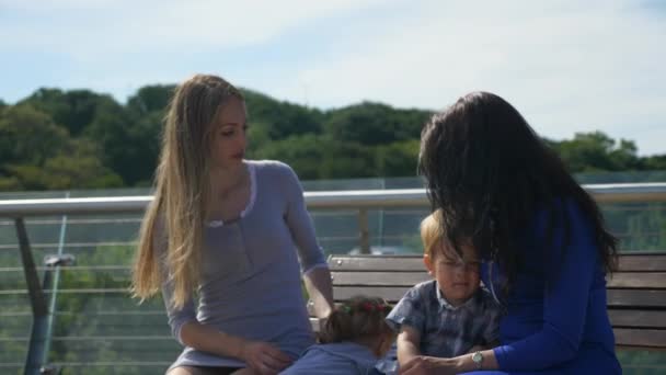 Happy Friends Mothers Sente Com Crianças Banco Ponte Pedonal Parque — Vídeo de Stock