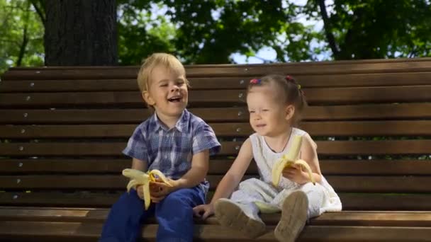 Счастливчик Девочка Сидят Скамейке Парке Дети Едят Бананы Светлый Солнечный — стоковое видео