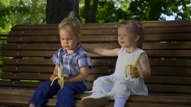 Happy Boy Girl Siedzą Ławce Parku Dzieci Jedzą Banany Jasny — Wideo stockowe