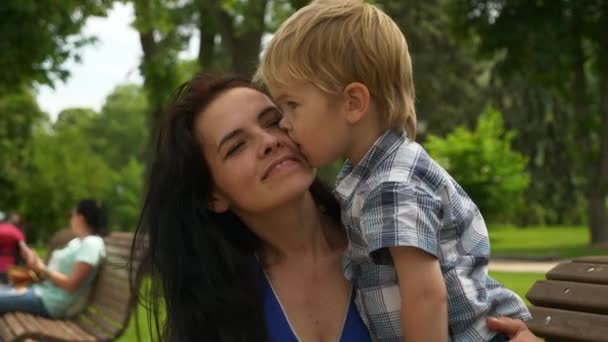 Sohn Küsst Mutter Mutter Mit Kind Ruht Auf Bank Stadtpark — Stockvideo